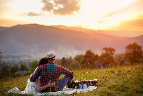 Final expense insured couple enjoy the sunset while picnicking.